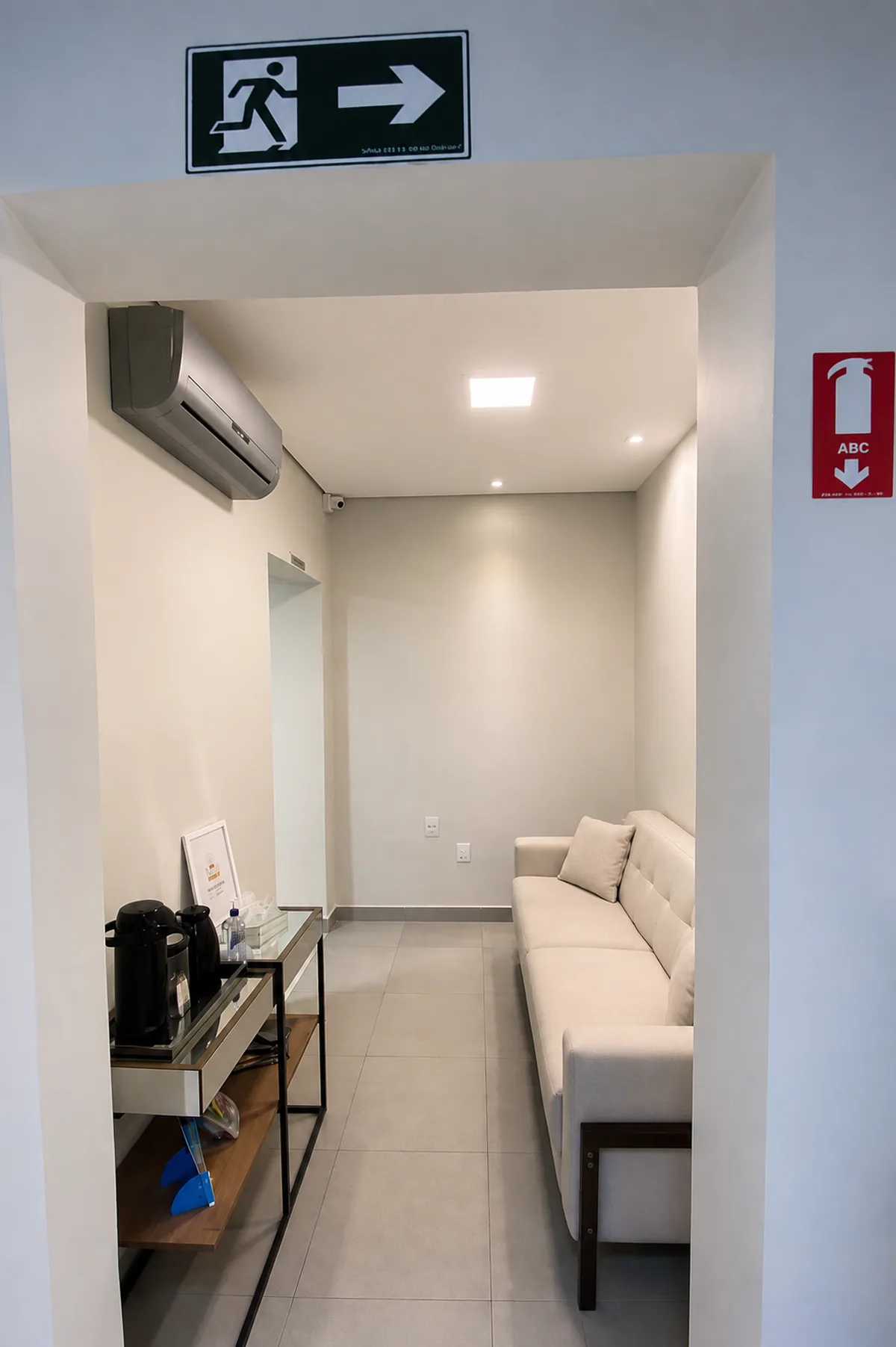 Segunda sala de espera da Clínica Laser Link, com sofá, ar-condicionado e estação de café e água